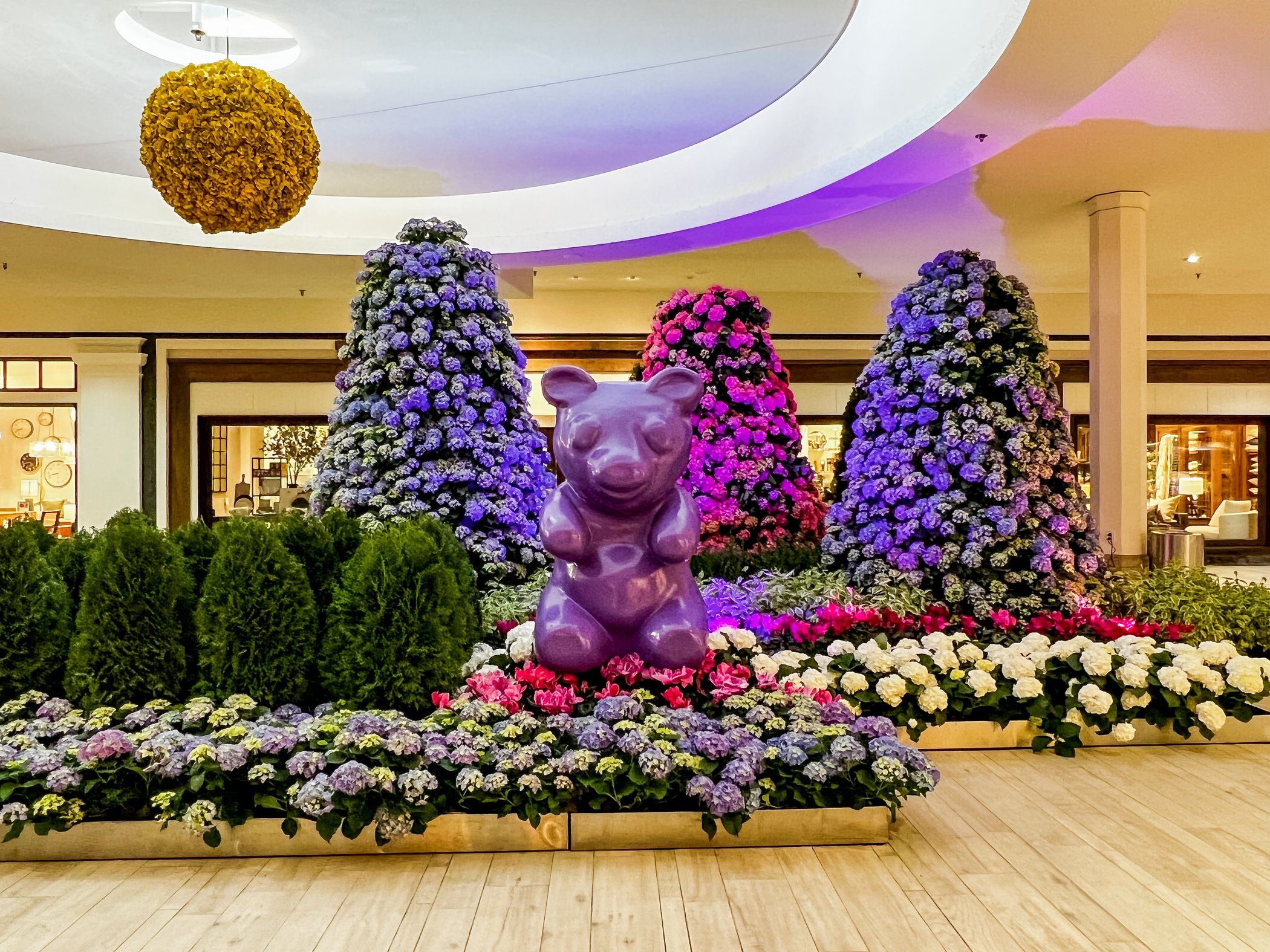 A 5-foot gummy bear sculpture stands amid a floral forest at the Galleria Shopping Center Sugar Coated Floral Experience.