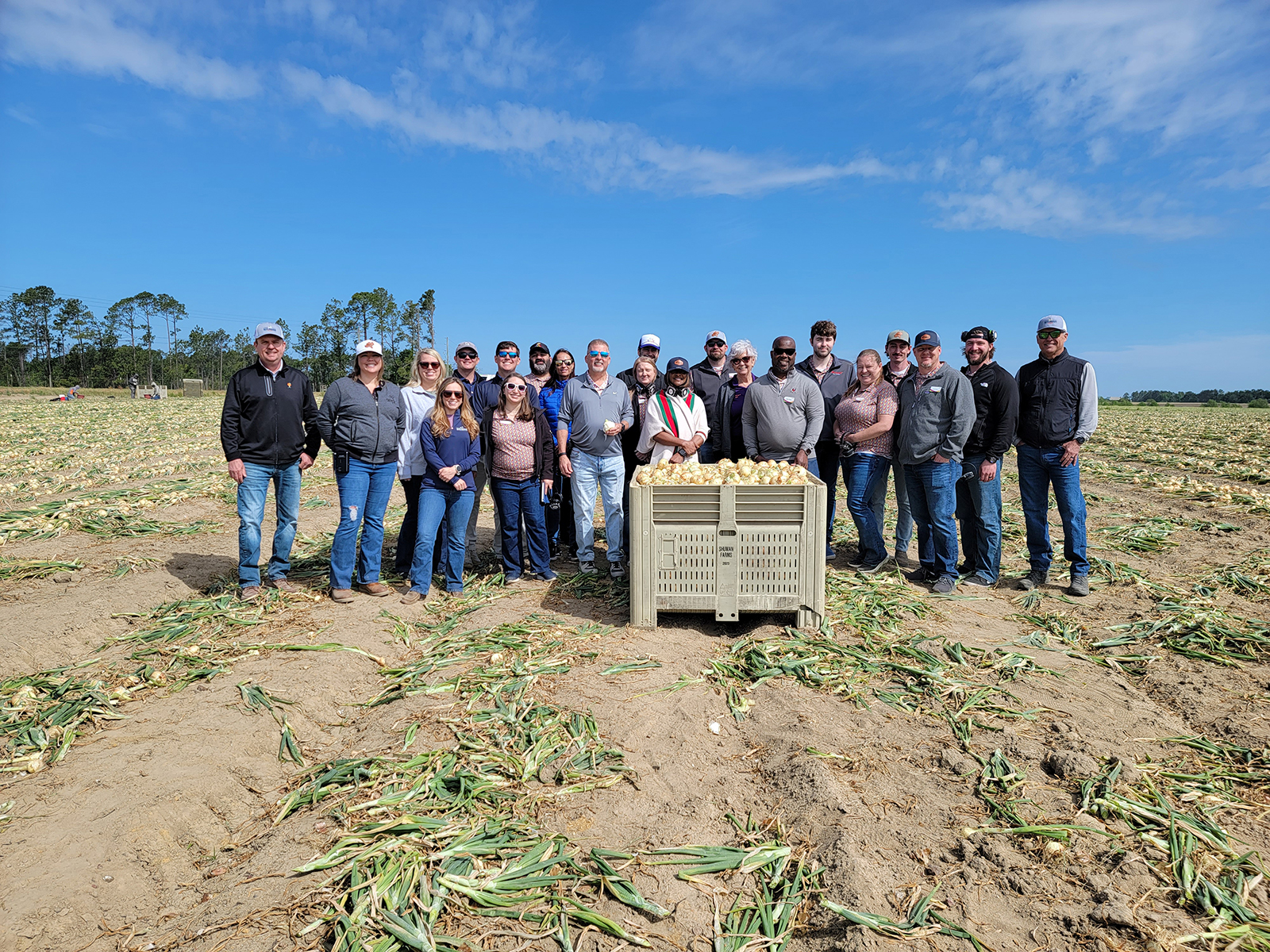Members of the Shuman Farms team with the class in one of their onion fields just before harvest.
